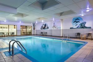 a pool in a hotel room with tables and chairs at Travelodge by Wyndham Quebec City Hotel & Convention Centre in Quebec City