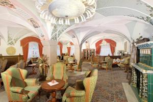 a room with chairs and tables and a chandelier at Hotel Dolomiti Schloss in Canazei