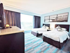 een hotelkamer met 2 bedden en een groot raam bij Thistle Johor Bahru in Johor Bahru