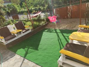 a backyard with a green lawn with chairs and a pool at Guest Rooms Profirov in Zlatograd