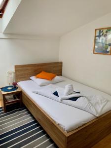 a bedroom with a bed with white sheets and an orange pillow at Hotel Orlan in Bratislava