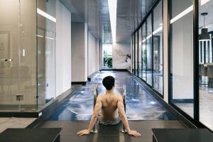 a man sitting in an indoor swimming pool in a building at CREW Hotel in Chiang Mai