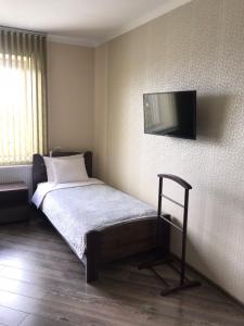 1 dormitorio con 1 cama y TV en la pared en Gray Hotel en Vynohradiv