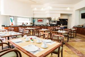 un restaurant avec des tables et des chaises en bois et une cuisine dans l'établissement Fiesta Inn Chihuahua, à Chihuahua