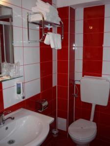 - une salle de bains rouge et blanche avec toilettes et lavabo dans l'établissement Hotel Sud, à Giurgiu