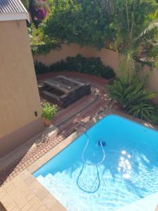 einen Pool mit einem Tisch und einer Bank im Hof in der Unterkunft The Leopard Tree in Polokwane