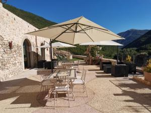 un patio con mesas, sillas y una sombrilla en Torre Del Nera Albergo diffuso & Spa en Scheggino