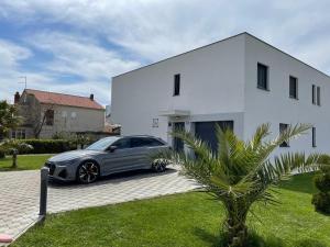 een auto geparkeerd voor een wit huis bij Apartment Castelli, 5 stars apartment in Kaštela