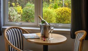 una mesa con una botella de vino y un cubo en Pinehurst Lodge Hotel - Aberdeen, en Dyce