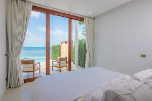 Schlafzimmer mit einem Bett und Meerblick in der Unterkunft White Whale Beachfront Pool Villa in Ban Bang Po