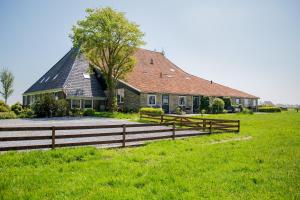 uma casa com uma cerca de madeira em frente em Boerderij Appartementen Ûnder de Wol - Súdwest Fryslân em Oudega