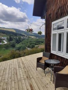 une terrasse en bois avec une table et des chaises dans un bâtiment dans l'établissement Cabana de pe stanca - hotel, à Cîrlibaba Nouă