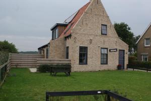 un vieux bâtiment en briques avec un banc devant lui dans l'établissement Antares-Ameland, à Hollum