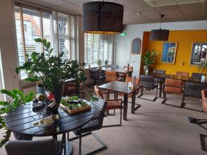斯容代克的住宿－Hotel de Zwaan，用餐室配有桌椅和植物