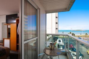 einen Balkon mit einem Tisch und Meerblick in der Unterkunft Hotel Santorini in Vila Velha