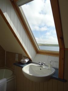 een badkamer met een wastafel en een raam bij The Sands Hotel, Orkney in Burray Village