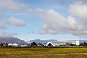 a white building in a field with mountains in the background at Hotel Jökull in Höfn