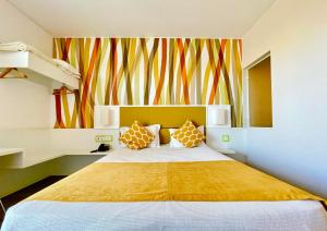 a bedroom with a large bed and a colorful wall at Hotel 3K Faro Aeroporto in Faro