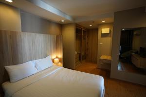 1 dormitorio con cama blanca y baño en Baan Tanwa - MRT Ratchadapisek en Bangkok