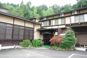 een gebouw met een parkeerplaats ervoor bij Ryokan Murayama in Takayama