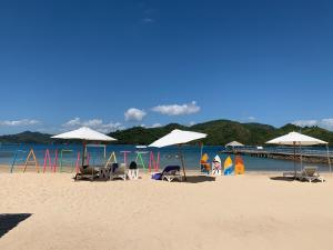 - une plage avec des chaises et des parasols et l'océan dans l'établissement Pangulatan Beach Resort, à El Nido