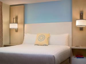 a bedroom with a large white bed with two lights at Sonesta ES Suites Chicago - Schaumburg in Schaumburg