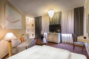 a hotel room with a bed and a couch and a tv at Villa St. Tropez in Prague