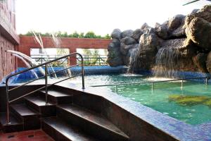 einen Pool mit Wasserfall und Treppe in einem Zoo in der Unterkunft Parklane Hotel in Mysore