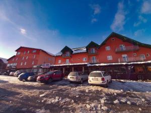 un grande edificio rosso con auto parcheggiate in un parcheggio di Hotel Lovac a Žabljak