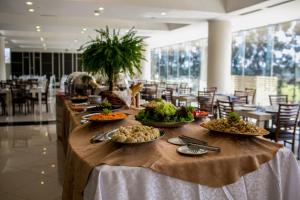 une longue table avec des assiettes de nourriture dans l'établissement Nobile Hotel Convention Ciudad Del Este, à Ciudad del Este