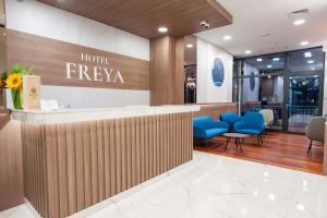 Hotel Freya في ستروغا: لوبي الفندق مع لوحة جدارية للفندق وكراسي زرقاء