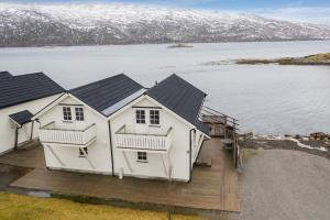 una gran casa blanca con una terraza junto a un cuerpo de agua en Idyllisk sjøhus på Naurstad en Bodø