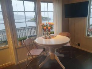 una mesa con flores y jarrones en ella en una habitación con ventanas en Idyllisk sjøhus på Naurstad en Bodø