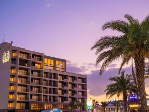 um hotel com palmeiras em frente a um edifício em MB GALLERY CHATAN by THE TERRACE HOTELS em Chatan