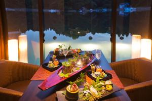 - une table avec deux assiettes de nourriture et des verres à vin dans l'établissement Noto Hyakurakusou, à Ogi