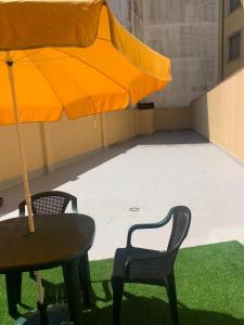 a table and two chairs and an orange umbrella at APARTAMENTO FONTE DO CRISTO in Porriño