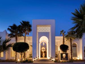 un edificio blanco con palmeras delante en Banyan Tree Tamouda Bay en Fnidek