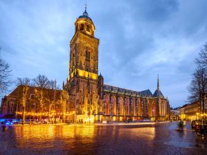 ein großes Gebäude mit einem Uhrturm in der Nacht in der Unterkunft Grand Boutique Hotel-Restaurant Huis Vermeer in Deventer