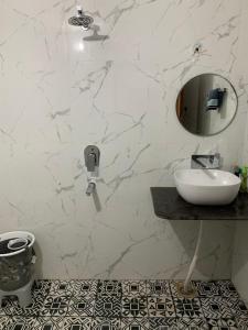 a white bathroom with a sink and a mirror at Bluetique in Varanasi