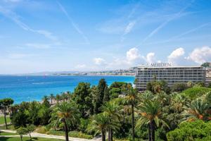 a view of a hotel and the ocean with palm trees at Le Meridien Nice in Nice