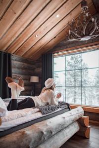 una donna sdraiata su un letto in una stanza con finestre di Wilderness Hotel Muotka & Igloos a Saariselka