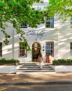 una mujer entrando en un edificio blanco en Oude Werf Hotel, en Stellenbosch