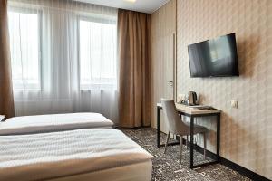 a hotel room with a desk and a tv on the wall at Citi Hotel's Łódź in Łódź