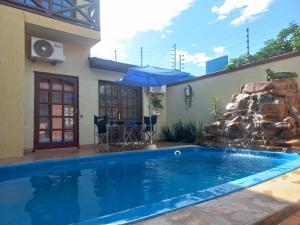 a swimming pool in front of a house with a waterfall at Salto dos hermanas in Puerto Iguazú