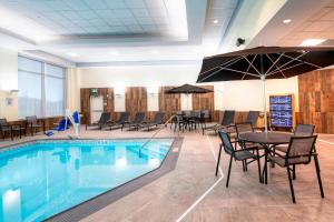 una piscina con mesas y sillas y una mesa con sombrilla en Fairfield Inn & Suites by Marriott Ottawa Airport, en Ottawa