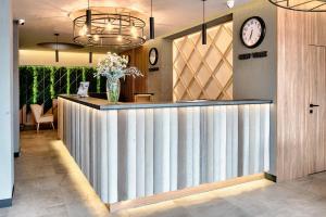 a lobby with a bar with a clock on the wall at Citi Hotel's Łódź in Łódź