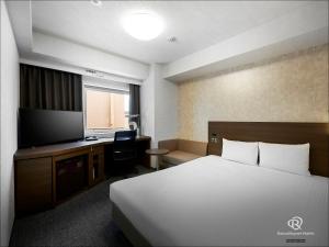 um quarto de hotel com uma cama, uma secretária e uma televisão em Daiwa Roynet Hotel Yokohama Kannai em Yokohama