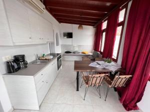 una cucina con armadi bianchi e tavolo con sedie di Birds Villa Apartments - Including Car Rental a Perissa