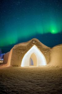 un iglú bajo las estrellas con las luces del norte en Arctic SnowHotel & Glass Igloos, en Sinettä