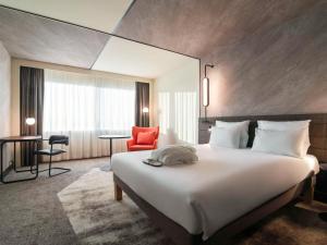 a hotel room with a large bed and a red chair at Novotel Rotterdam Brainpark in Rotterdam